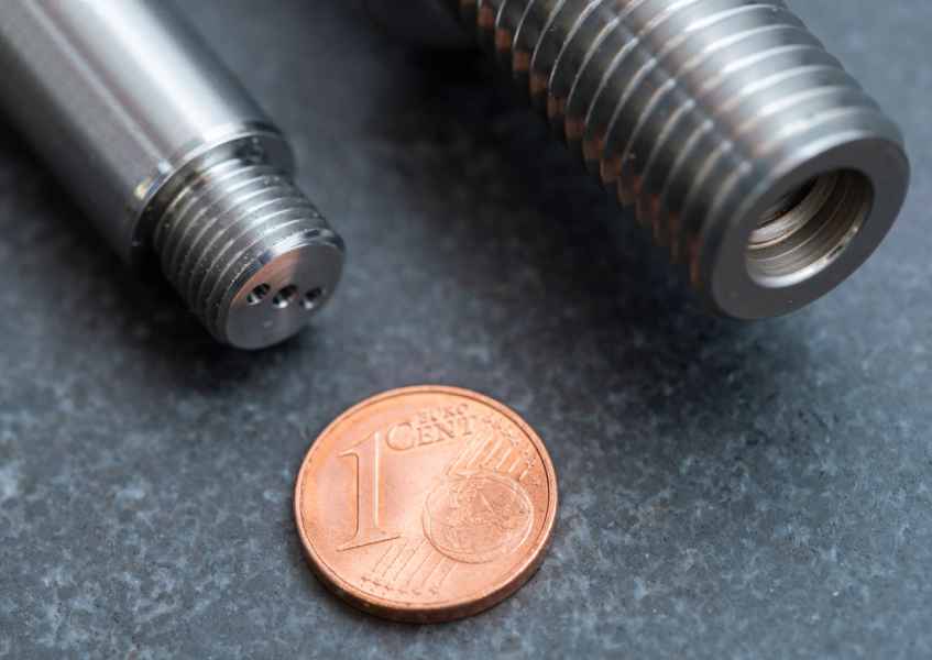 Gewindeteile neben einer 1-Cent-Münze